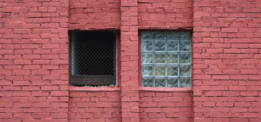 Cam bloklardan yapılmış bir pencere ve kırmızı tuğla duvardaki parmaklıklı bir pencere.