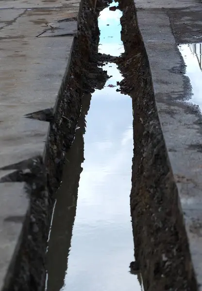 A narrow channel dug in the ground with water at the bottom