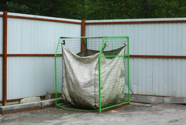 Kullanılmış plastik şişeleri toplamak için poşeti olan yeşil metal bir kap.