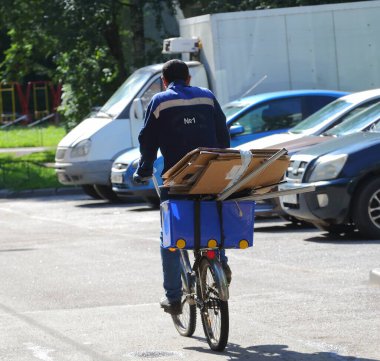 Bisikletli mavi üniformalı atık toplayıcısı Bolşevikov, Saint Petersburg, Rusya Ağustos 2020