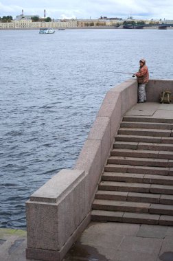 Granit nehir kıyısında elinde olta olan balıkçı, Dvortsovaya Embankment, Saint Petersburg, Rusya, Ekim 2020