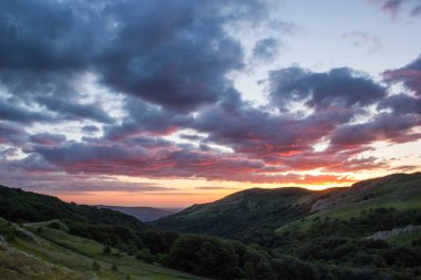 Yansıma Golden Sunset Green Hills yaz manzara sırasında güneş kırmızı ile ağır kara bulutlar