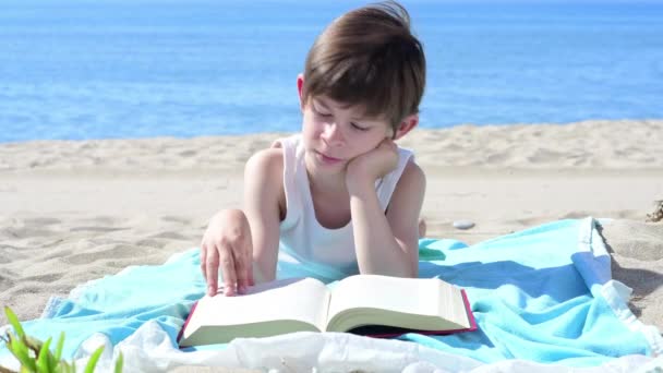 Ragazzo Legge Libro Sdraiato Sulla Spiaggia Guarda Cielo — Video Stock
