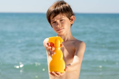 çocuk plajda güneş kremi gösterir