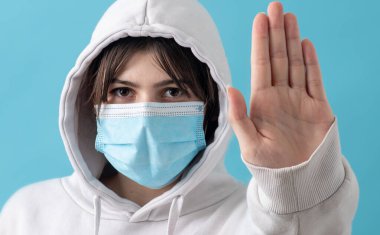 Hijyenik maskeli bir kız, 19 'dan önce eliyle mesafeyi işaret ediyor.