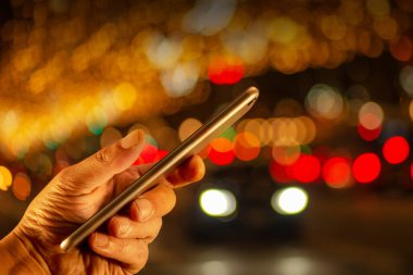 Şehirde geceleri sıcak ışıkları olan akıllı telefonlara el feneri takar.