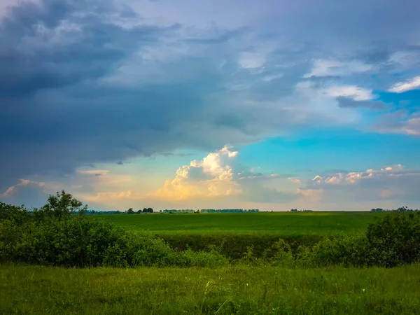 Cumulus bulutları ile mavi gökyüzü altında günbatımı Parlatıcı güzel yeşil kırsal manzara