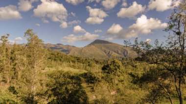 Günbatımının ışığıyla aydınlatılan görkemli Iguaque dağı yamacındaki ormanlarla ve çiftliklerle ve vadideki körükle.