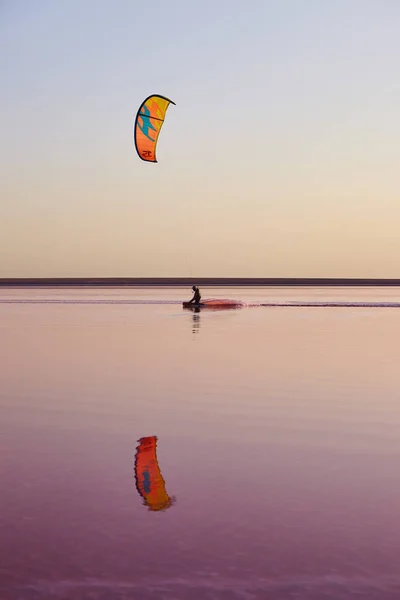 Kitesurfing on pink color lake with reflection — Stock Photo, Image