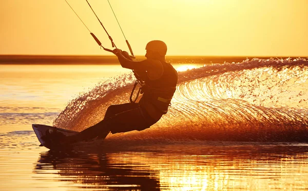 Kitesurfer на заході сонця з бризками води — стокове фото