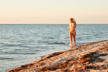 Bir kız denizin yanından geçiyor.