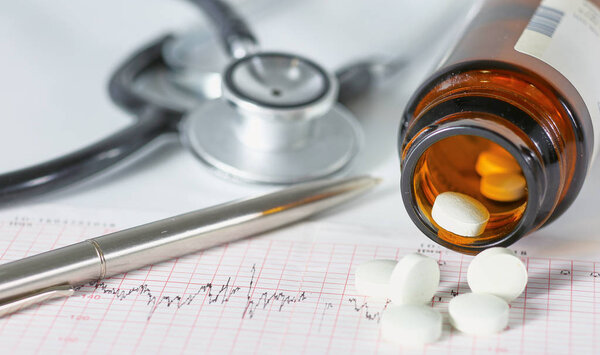 стетоскоп, таблетки, ампулы в медицинском кабинете на синем фоне
