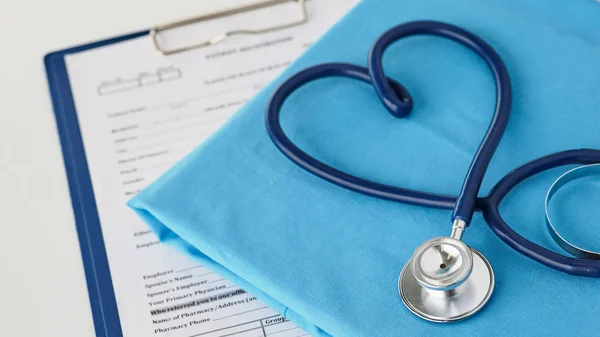 Un estetoscopio dando forma a un corazón en un uniforme médico, primer plano, enfoque selectivo —  Fotos de Stock