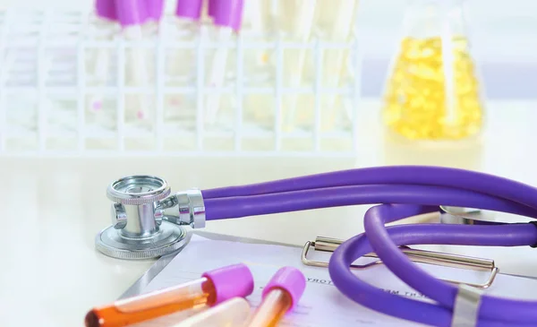 Närbild av skrivbordet av en läkare med ett stetoskop i förgrunden och en flaska med piller i bakgrunden — Stockfoto