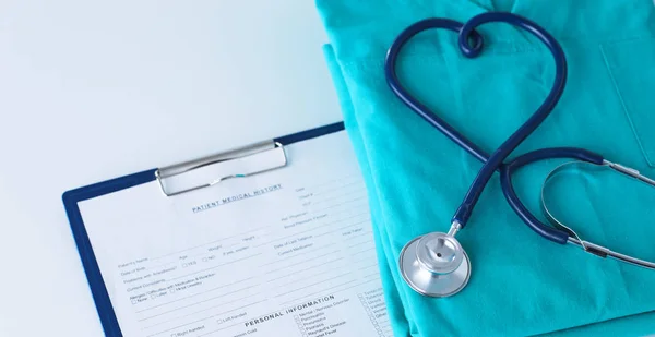 Un estetoscopio dando forma a un corazón en un uniforme médico, primer plano, enfoque selectivo — Foto de Stock