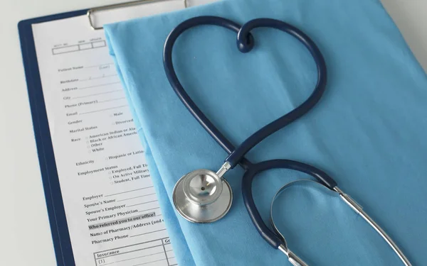 Un estetoscopio dando forma a un corazón en un uniforme médico, primer plano, enfoque selectivo —  Fotos de Stock