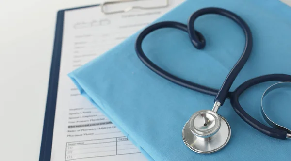 Un estetoscopio dando forma a un corazón en un uniforme médico, primer plano, enfoque selectivo —  Fotos de Stock