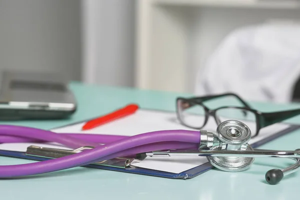 Doktorların çalışma alanı çalışma tablosu hastalar deşarj boş kağıt formu, tıbbi reçete, stetoskop üstünde okul sırası ile — Stok fotoğraf
