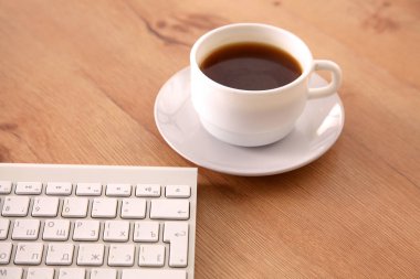 Ofis resepsiyon masası bilgisayar, sarf malzemeleri ve kahve fincanı ile