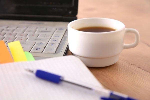 Mesa de escritório com bloco de notas em branco e laptop — Fotografia de Stock