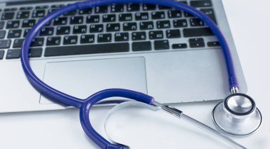 Bir dizüstü bilgisayar klavye online tıp kavramı içinde yatan veya bilgisayar sorun giderme stetoskop düşük açılı kopya alanı ile görüntülendi