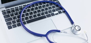 Bir dizüstü bilgisayar klavye online tıp kavramı içinde yatan veya bilgisayar sorun giderme stetoskop düşük açılı kopya alanı ile görüntülendi