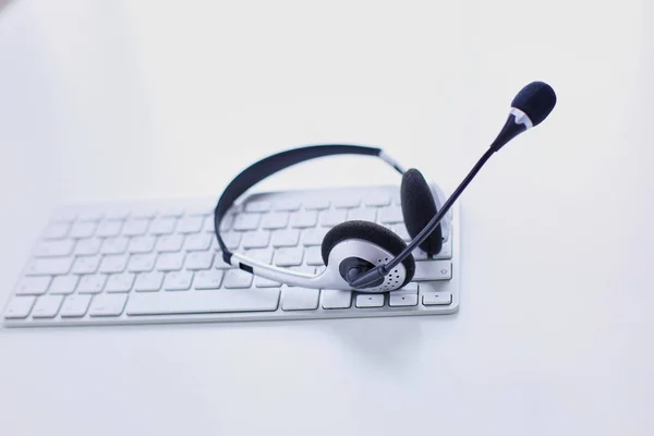 Soporte de comunicación, call center y servicio de atención al cliente. Auriculares VOIP en el teclado del ordenador portátil — Foto de Stock