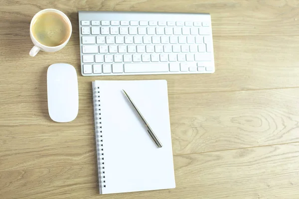 Mesa de escritório com teclado de computador, notebook com caneta e xícara de café na mesa — Fotografia de Stock