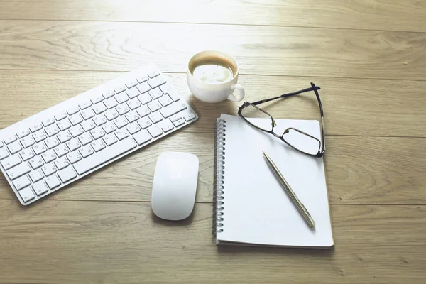 Mesa de escritório com teclado de computador, notebook com caneta e xícara de café na mesa — Fotografia de Stock