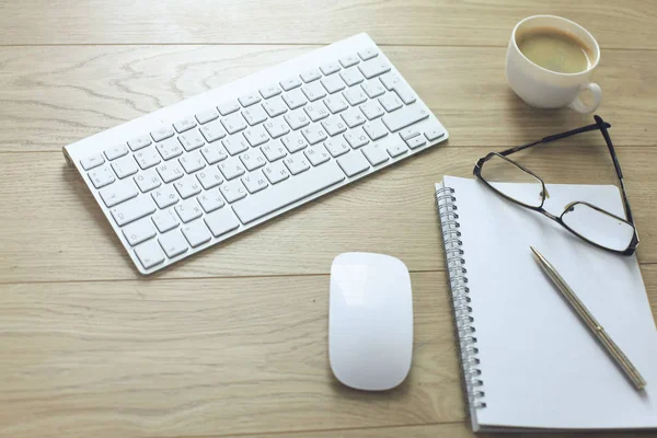 Table de bureau avec clavier d'ordinateur, ordinateur portable avec stylo et tasse à café sur le bureau — Photo