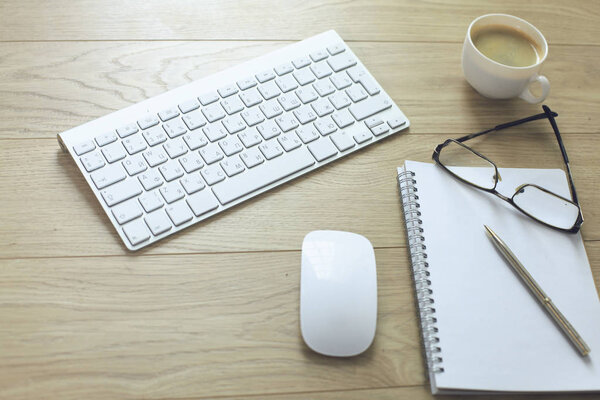 office desk table with computer keyboard, notebook with pen and coffee cup on desk