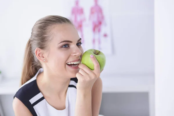 Unga vackra leende flicka med ett grönt äpple i händer — Stockfoto