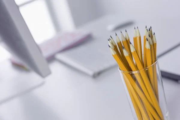 Графитовые карандаши в стеклянной чашке на рабочем столе. Концепция — стоковое фото