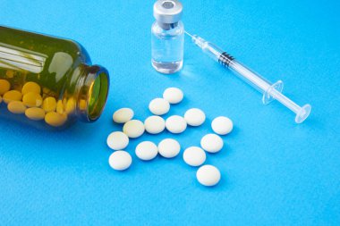 Beyaz hap ve ilaçlar masada bir şırınga ile kahverengi cam şişe