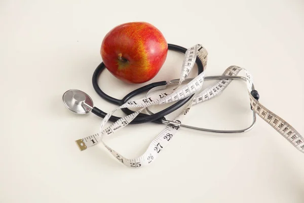 Manzana, cinta métrica y un estetoscopio sobre la mesa — Foto de Stock