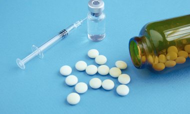 Beyaz hap ve bir ilaç bir şırınga ile kahverengi cam şişe