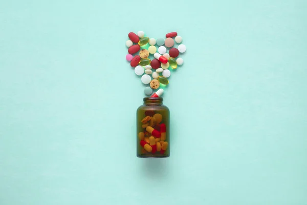 Pequeño frasco de vidrio con pastillas derramadas sobre una mesa —  Fotos de Stock