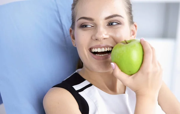 Unga vackra leende flicka med ett grönt äpple i händer — Stockfoto