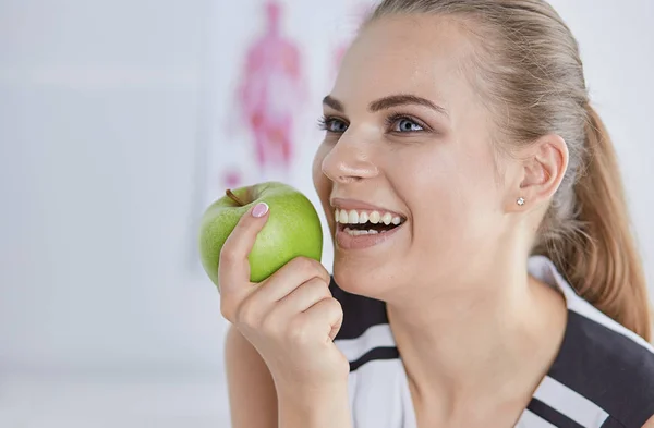 Unga vackra leende flicka med ett grönt äpple i händer — Stockfoto