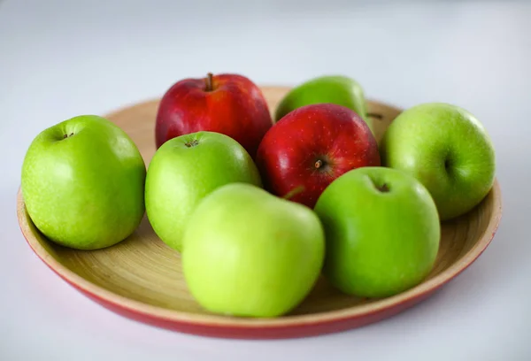 Дерев'яна тарілка зі стиглими свіжими червоними та зеленими яблуками — стокове фото