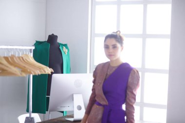 Pano raf giysi tasarımcısı ile yakınındaki beyaz arka plan üzerinde tutan güzel genç stilist