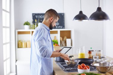 Gülümseyen ve kendinden emin şef büyük mutfakta duruyor.