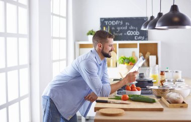 Gülümseyen ve kendinden emin şef büyük mutfakta duruyor.