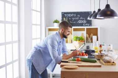 Gülümseyen ve kendinden emin şef büyük mutfakta duruyor.