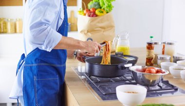 Gülümseyen ve kendinden emin şef büyük mutfakta duruyor.