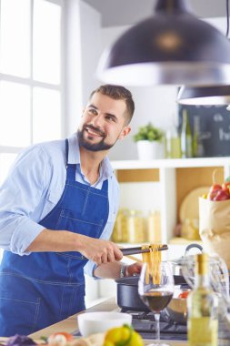 Gülümseyen ve kendinden emin şef büyük mutfakta duruyor.