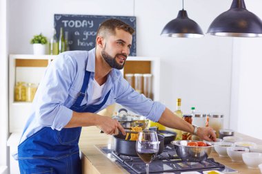 Gülümseyen ve kendinden emin şef büyük mutfakta duruyor.