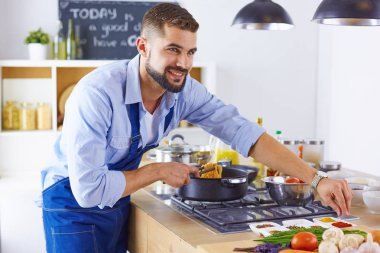 Gülümseyen ve kendinden emin şef büyük mutfakta duruyor.