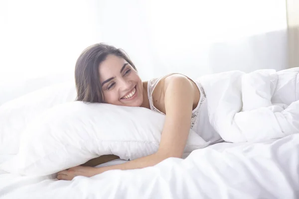 Bela jovem mulher se aquecendo na cama pela manhã. Cara modelo bonita parece sexy na câmera — Fotografia de Stock