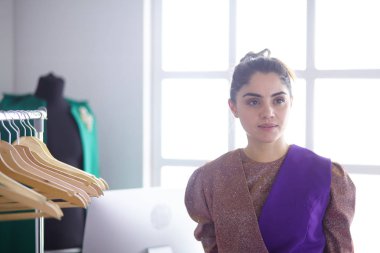Pano raf giysi tasarımcısı ile yakınındaki beyaz arka plan üzerinde tutan güzel genç stilist